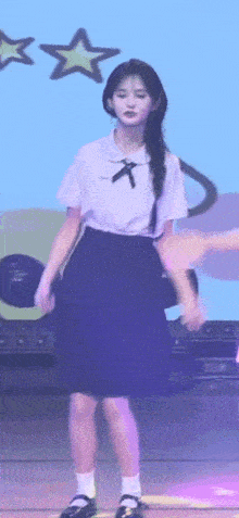 a young girl in a school uniform is standing on a stage .