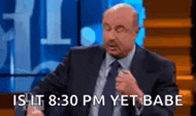 a bald man in a suit and tie is sitting on a stage .