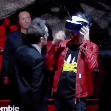 a man in a red jacket is talking to another man in a black shirt with a duck on it .