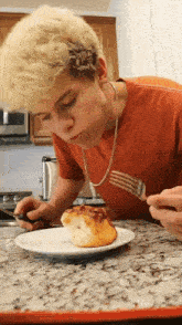 a young man eating a pastry with a fork and knife