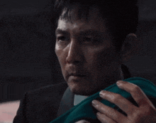 a man in a suit and tie is holding a green cloth in his hand