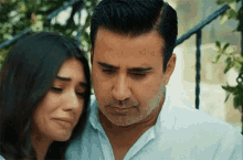 a man and a woman are hugging each other and the woman is crying