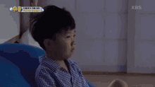 a little boy is yawning with a kbs logo in the background