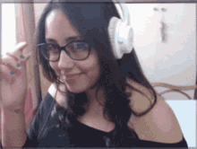 a woman wearing glasses and white headphones is smiling