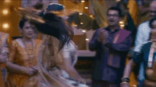 a woman is dancing in front of a crowd of people at a wedding reception .