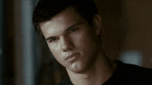 a young man in a black shirt looks at the camera