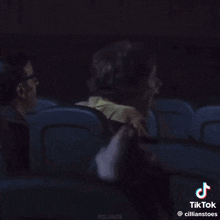 a man wearing sunglasses is talking to another man in a dark room