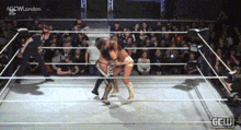 two women are wrestling in a ring with a crowd watching and a sign that says gcw london