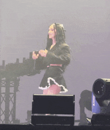 a woman is standing on a stage holding a microphone and dancing .
