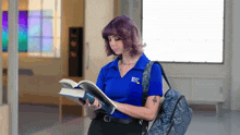 a woman wearing a blue shirt that says best buy is reading a book