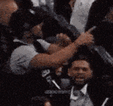 a group of people are sitting in a stadium and a man is pointing at another man .