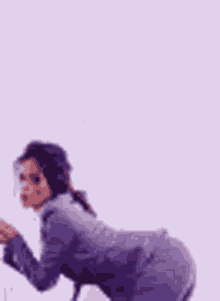 a woman in a purple suit is holding a cane while kneeling down .