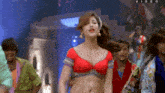 a woman in a red top is dancing in front of a group of people with the word video on the bottom