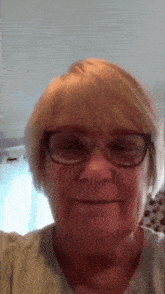 a woman wearing glasses and a green shirt is smiling for the camera