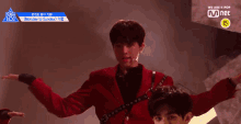 a man in a red jacket is dancing on a stage in front of a mnet logo