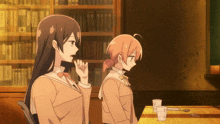 two anime girls are sitting at a table with cups