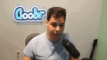 a man is sitting in front of a microphone in front of a sign that says coobr