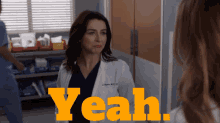 a woman in a lab coat stands in front of a sign that says " yeah "