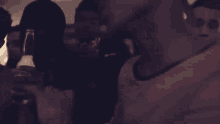 a group of people are gathered in a dark room and one man is holding a glass