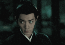 a close up of a man 's face with a serious look on his face in a dark room .