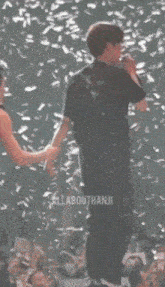 a group of people holding hands on a stage with the word allabouthanj written on the bottom right