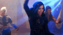 a woman in a blue jacket is dancing in a dark room with other people .