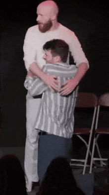 two men hugging each other on stage in front of a crowd