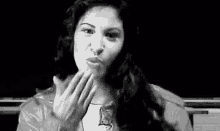 a woman is laughing in a black and white photo while covering her mouth with her hands .