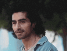 a man with long hair and a blue shirt smiles