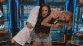 a woman is carrying another woman on her shoulders while wearing a aew belt .