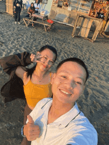 a man giving a thumbs up next to a woman on the beach