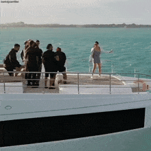 a group of people standing on the deck of a boat with a woman taking a picture of them