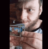 a man with a beard is holding up a card with a picture of a dog on it