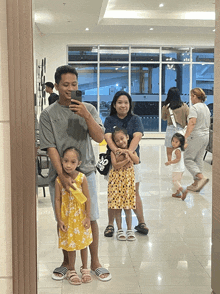 a man is taking a picture of his family in front of a mirror with a bag that says ' adidas ' on it