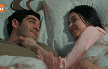 a man and a woman are laying in bed with a tv logo on the corner
