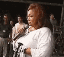 a woman is holding a microphone in front of a crowd of people .