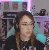 a woman wearing headphones and glasses is sitting in front of a renrize sign