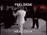 a man in a white suit is dancing in front of a crowd .