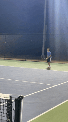 a man is playing tennis on a court at night