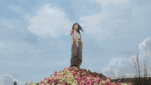 a person standing on top of a pile of pink and yellow flowers
