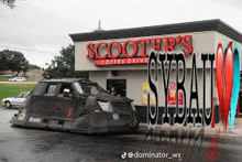 a scooter 's coffee drive in a city with a car parked in front of it .