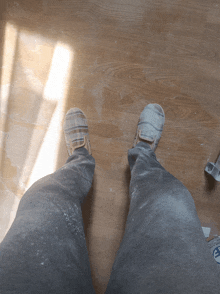 a person standing on a wooden floor wearing a pair of shoes that say ' converse ' on them