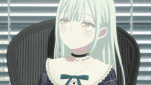 a girl with white hair is sitting in a chair in front of blinds