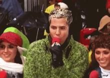 a man in a green sweater is holding a microphone