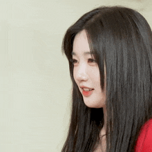 a woman with long black hair and a red shirt is smiling