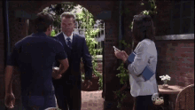 a man in a suit and tie is talking to a woman who is holding a cellphone