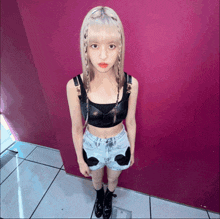 a woman wearing a black crop top and denim shorts