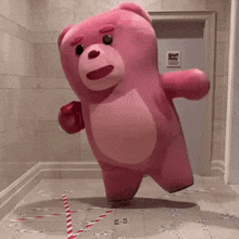 a pink teddy bear is standing in a hallway with a sign that says staff only