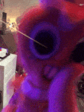 a blurry picture of a person holding a red toy gun with purple lights behind it .