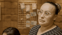 a woman wearing glasses and a striped shirt looks at something